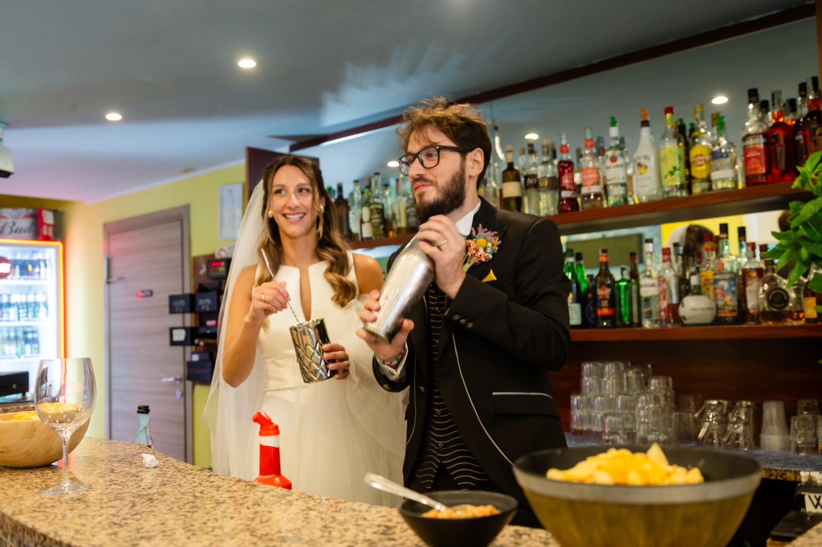 Gli sposi preparano cocktail dietro il bancone del bar durante la festa