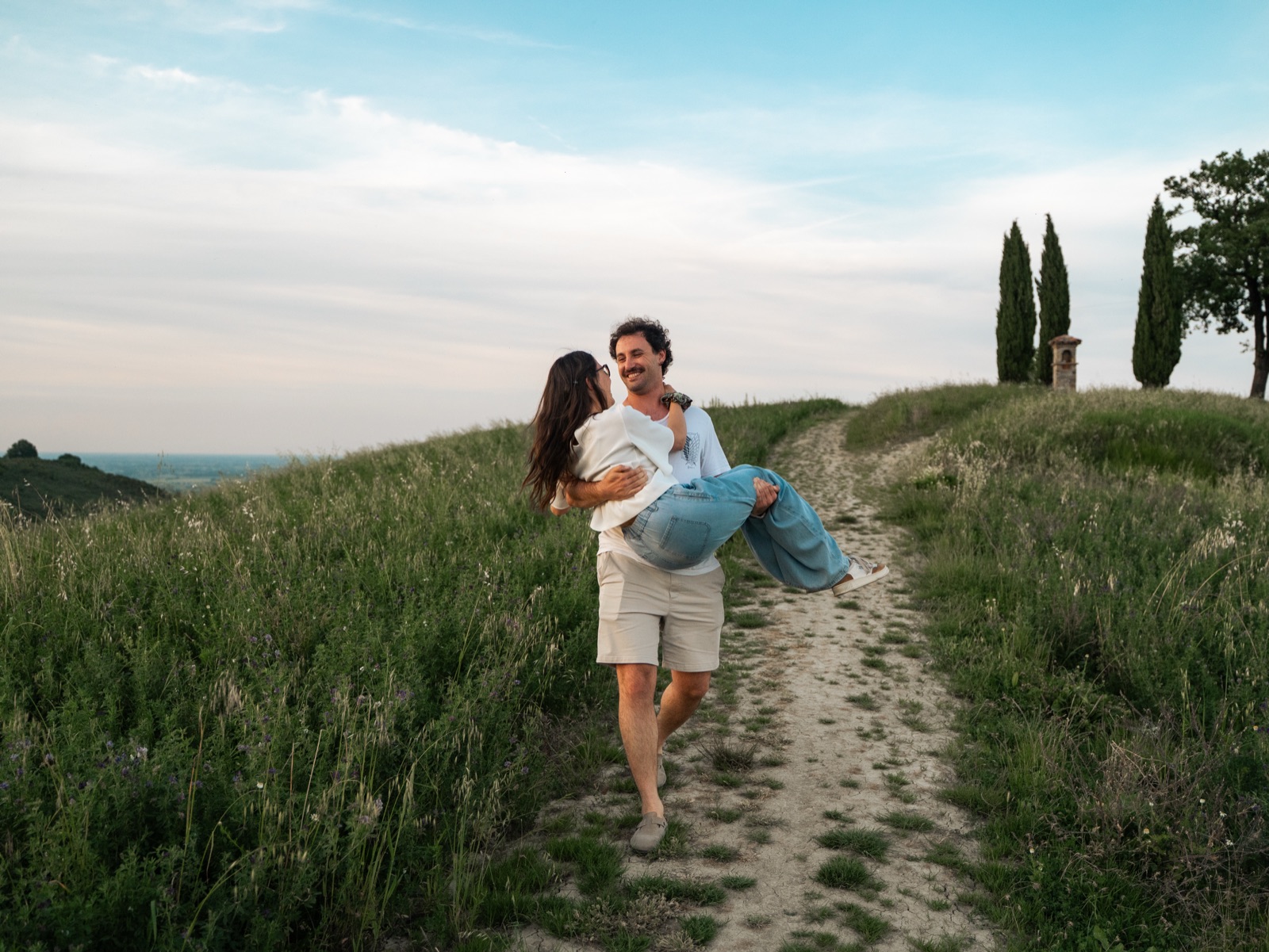 Lo sposo porta in braccio la sposa lungo un sentiero tra le colline