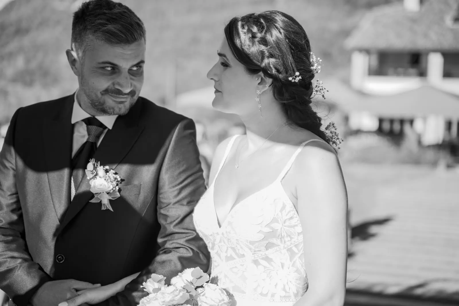 Ritratto in bianco e nero: lo sposo sorride di sbieco guardando la sposa, che lo guarda di profilo